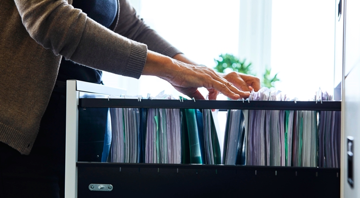 Person kigger efter sagsmappe i skuffe