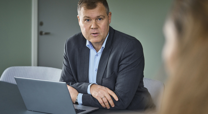 Jens Baagøe Thomsen siddende ved bærbar og snakker med kvinde