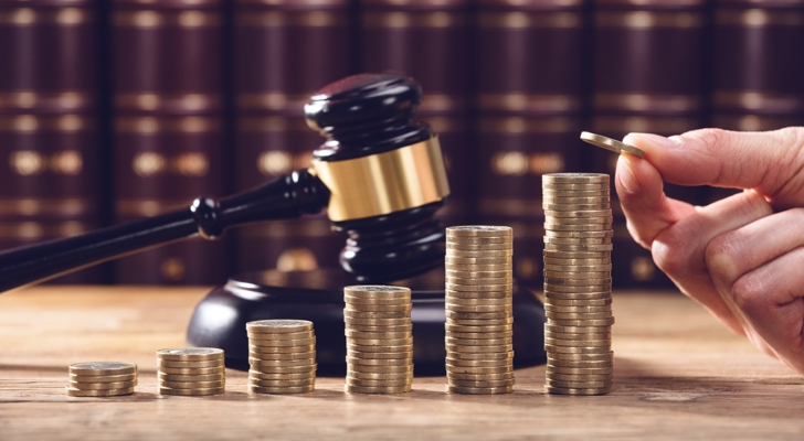 Hænder der stabler mønter med dommergavel i baggrunden